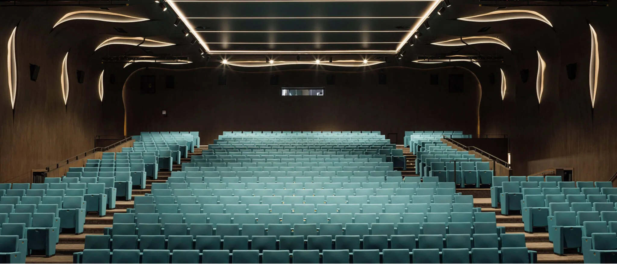 Sala cinema con poltrone verde acqua e soffitto luminoso su misura